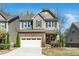 Charming two-story home featuring a stone and siding exterior with a two-car garage and manicured lawn at 936 Regency Cottage Pl, Cary, NC 27518