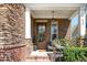 Charming front porch with stone accents, decorative wreath, and cozy seating area with a brick pathway at 936 Regency Cottage Pl, Cary, NC 27518