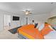 Bright bedroom featuring a ceiling fan, television, and a comfortable bed with orange bedding at 95 Shady Creek Trl, Garner, NC 27529