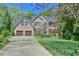 Traditional brick home featuring a two-car garage, manicured lawn, and mature landscaping at 104 Buckeye Ln, Chapel Hill, NC 27516