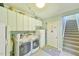 Well-organized laundry room with modern washer, dryer, and ample cabinet space next to carpeted stairs at 104 Buckeye Ln, Chapel Hill, NC 27516