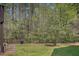 Lush backyard featuring mature trees, lawn, wooden planter, and iron fence at 104 Lowe Wood Ct, Durham, NC 27703
