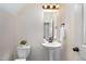 This half bath features a pedestal sink, decorative mirror, and classic fixtures at 104 Lowe Wood Ct, Durham, NC 27703
