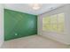 Modern bedroom with a decorative green wall, one window, and light carpet at 104 Lowe Wood Ct, Durham, NC 27703