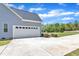 Attached garage with a white door and a paved driveway surrounded by landscaped shrubs and greenery at 1077 Williams-White Rd, Zebulon, NC 27597