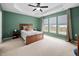 Green-walled bedroom offers a wood bed frame, neutral carpet, and large windows with ample sunlight at 1103 Kudzu St, Durham, NC 27713