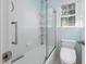 Bathroom offers a white tiled shower-tub with sliding glass door and window with blinds at 125 Kelekent Ln, Cary, NC 27518