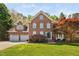 Beautiful two-story brick home with a well-manicured lawn and lush landscaping, including colorful trees at 125 Kelekent Ln, Cary, NC 27518