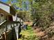 A view of the backyard features a wooden deck with stairs, lush greenery, and a gentle slope down to the yard at 1308 Oakridge Ave # 3, Henderson, NC 27536
