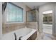 Luxurious bathroom featuring a soaking tub, a glass-enclosed shower, and tiled walls at 2204 Secluded Oaks Ct, Wake Forest, NC 27587