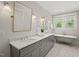 Bright bathroom featuring a double vanity, large mirror, hexagon tile floors, and a clawfoot bathtub under a window at 2416 W Club Blvd, Durham, NC 27705
