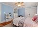 Bright blue bedroom features hardwood floors, a plush rug, built-in shelving, and a ceiling fan at 2416 W Club Blvd, Durham, NC 27705