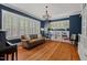 Stylish living room with dark blue walls, hardwood floors, built-in bookshelves, and modern chandelier at 2416 W Club Blvd, Durham, NC 27705