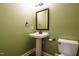 Powder room with pedestal sink, toilet, black framed mirror, and olive green walls at 2916 Rue Sans Famille, Raleigh, NC 27607