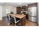 Open kitchen with an island, stainless steel appliances, and dark wood cabinets at 317 City Center Ln, Wendell, NC 27591