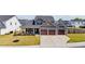 Charming home featuring a three-car garage, landscaped yard, and cozy front porch with seating at 34 Tea Olive Ct, Clayton, NC 27520