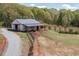 White barn with a metal roof and three stalls on a horse property surrounded by lush trees at 3787 Pleasant Hill Church, Siler City, NC 27344