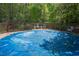 Backyard pool with surrounding deck area, partially covered with a blue tarp for protection, set among trees at 3787 Pleasant Hill Church, Siler City, NC 27344