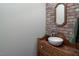 Charming powder room with a brick accent wall, vessel sink, wood vanity, decorative mirror, and stylish fixtures at 3787 Pleasant Hill Church, Siler City, NC 27344