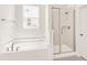All-white bathroom with separate tub and shower featuring glass doors and modern fixtures at 40 Rosewood Ln, Youngsville, NC 27596
