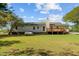 Grassy backyard view showcasing the home's exterior, an elevated wooden deck, and a large propane tank at 413 Bayles Rd, Lillington, NC 27546