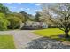 A sunny day shows the front of the home with flowering trees near the driveway at 413 Bayles Rd, Lillington, NC 27546