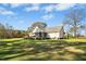 A spacious backyard featuring a large lawn, mature trees, a screened porch, and a deck area at 460 Mann Rd, Coats, NC 27521