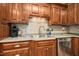 Close up of kitchen featuring dark wood cabinets, stainless steel dishwasher, and tiled backsplash at 460 Mann Rd, Coats, NC 27521