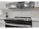Modern range hood above stainless steel oven and stove top with light-gray tiled backsplash at 4720 Brigadoon Dr, Durham, NC 27705