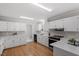 Stylish kitchen featuring white cabinets, modern appliances, and hardwood floors, perfect for cooking at 4720 Brigadoon Dr, Durham, NC 27705