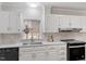 Well-lit kitchen with stainless steel appliances, white cabinets, tiled backsplash, and a window over the sink at 4720 Brigadoon Dr, Durham, NC 27705