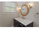 Well-lit bathroom features a custom vanity with gold hardware, a round mirror and a window at 5212 Theys Rd, Raleigh, NC 27606