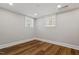 Clean, spacious bedroom with hardwood floors, two windows, and neutral wall color at 5212 Theys Rd, Raleigh, NC 27606