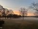 Picturesque landscape featuring a misty meadow, lined with mature trees against a stunning sunrise at 5212 Theys Rd, Raleigh, NC 27606