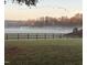 Scenic view of a property shrouded in mist, with horses grazing peacefully behind a rustic fence at 5212 Theys Rd, Raleigh, NC 27606