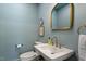 Stylish powder room with blue walls, a decorative mirror and brass fixtures at 5212 Theys Rd, Raleigh, NC 27606