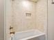 Bright shower area features cream-colored tiling, a niche and gold fixtures over a white tub at 5212 Theys Rd, Raleigh, NC 27606
