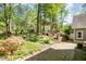 Manicured backyard featuring landscaping, stone walkway, and a cozy pergola at 6105 Splitrock Trl, Apex, NC 27539