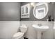 Elegant bathroom with a pedestal sink, wainscoting, and a round mirror at 6105 Splitrock Trl, Apex, NC 27539