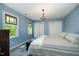 Cozy bedroom with blue walls, a decorative chandelier, and natural light from stained glass windows at 6105 Splitrock Trl, Apex, NC 27539