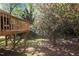 Wooden deck and blossoming tree in a lush, green backyard offering a tranquil outdoor space at 703 Midsummer Ln, Apex, NC 27502