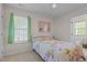 Cozy bedroom featuring a bed with floral bedding, a window with light-green curtains, and ensuite bath at 703 Midsummer Ln, Apex, NC 27502