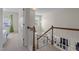 Bright hallway featuring a wooden railing, neutral walls, and a view into the living room at 703 Midsummer Ln, Apex, NC 27502