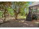 Landscaped backyard featuring mature trees and a brick paver patio with stairs leading to a screened-in porch at 720 Raymond Dr, Clayton, NC 27527