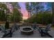 Outdoor patio area with a stone fire pit and Adirondack chairs overlooking a peaceful lakeside view at 775 Sagamore Dr, Louisburg, NC 27549