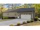 Attached garage with clean, white door and lush landscaped grounds on a sunny day at 775 Sagamore Dr, Louisburg, NC 27549