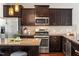 Close-up of the kitchen with stainless appliances, dark cabinets and a granite countertop island at 7822 Allscott Way, Raleigh, NC 27612