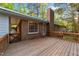 The wooden back deck overlooks the backyard with access to the home through a glass door and brick chimney at 801 Silver Leaf Pl, Raleigh, NC 27609