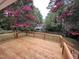 Relaxing wooden back deck surrounded by trees and vibrant pink flowers at 801 Silver Leaf Pl, Raleigh, NC 27609