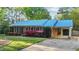 Charming brick home with a striking blue metal roof, lush landscaping, and a convenient carport at 801 Silver Leaf Pl, Raleigh, NC 27609